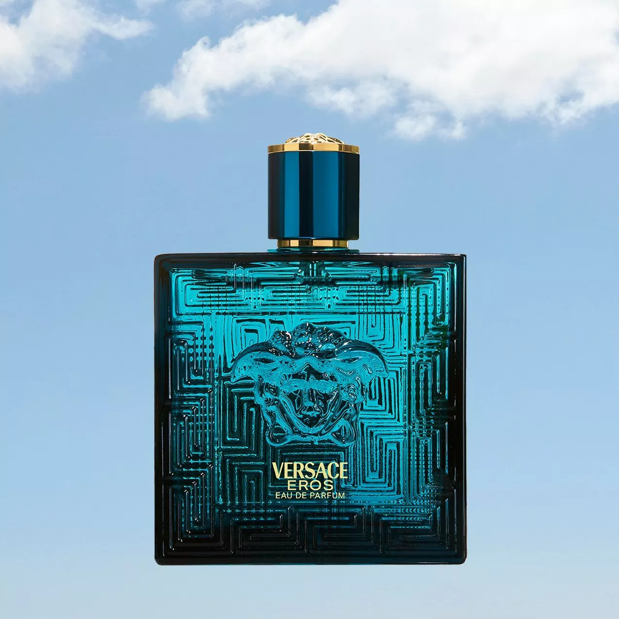 Versace Eros Eau de Parfum bottle in turquoise glass with gold cap, product shot on blue sky background
