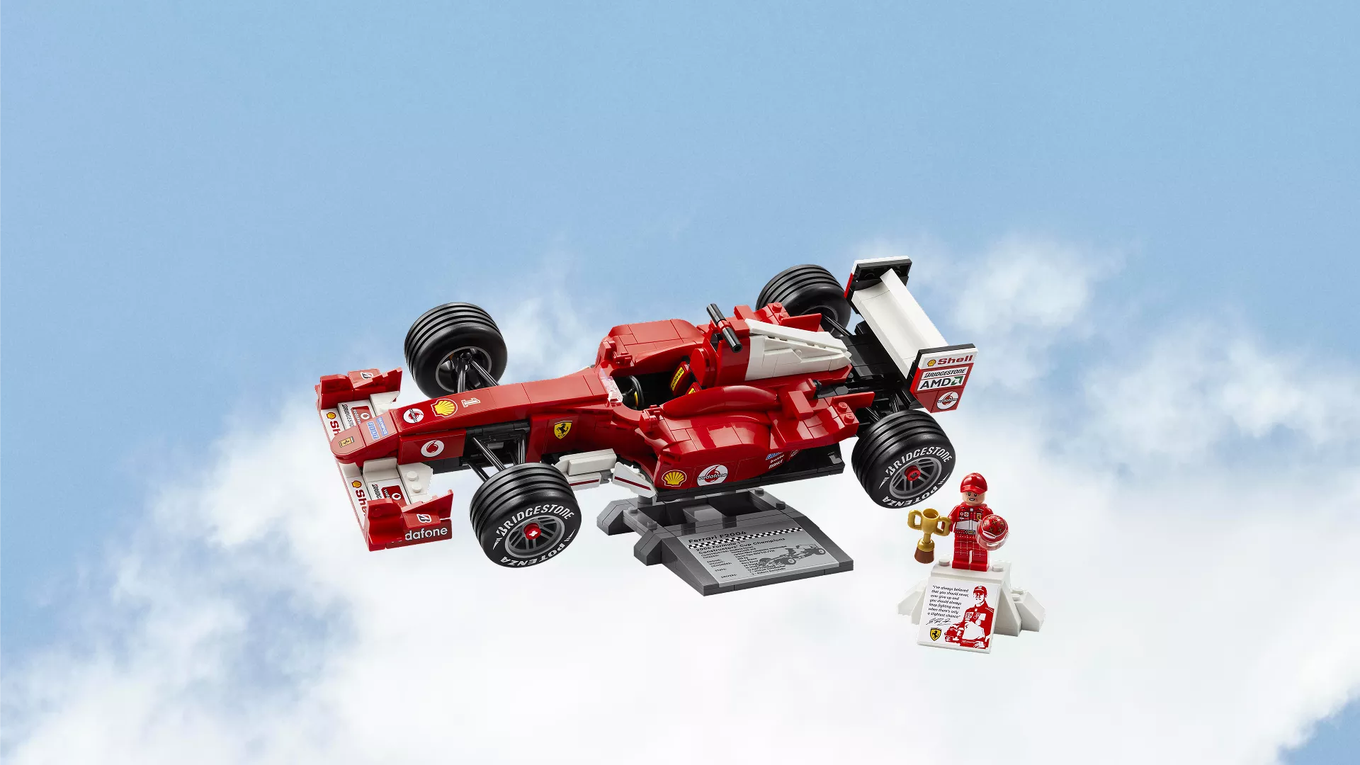 LEGO Ferrari F1 race car model with driver minifigure and trophy display stand against blue sky background