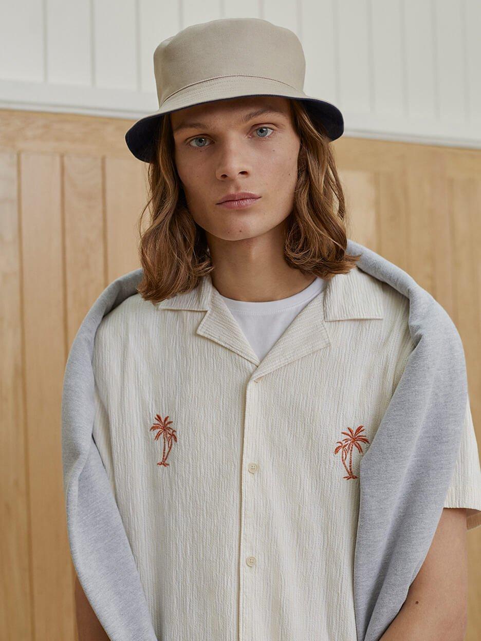 Model in palm tree print shirt and hat