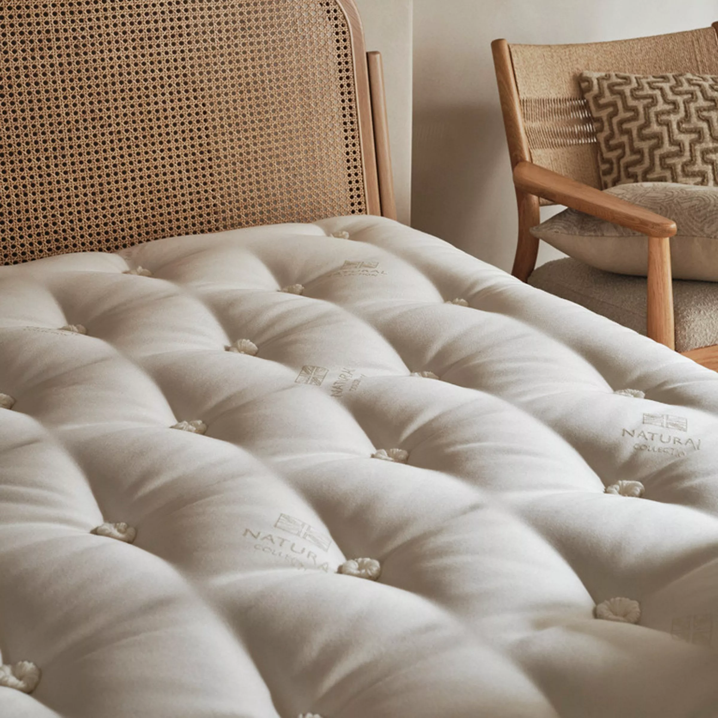 Mattress on a rattan bed with a wooden chair next to the bed
