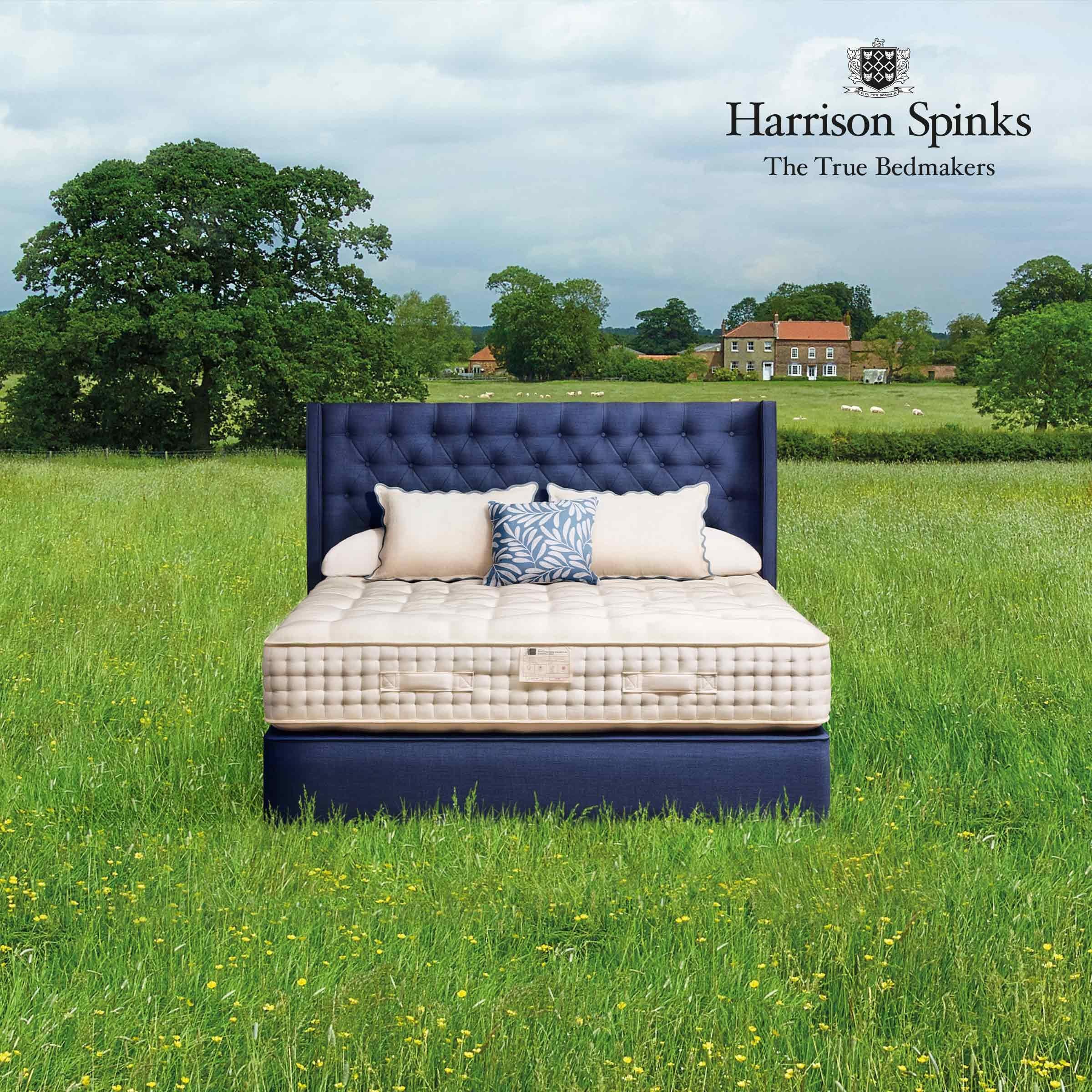 Harrison Spinks mattress in a green field with a farm house and sheep in the background