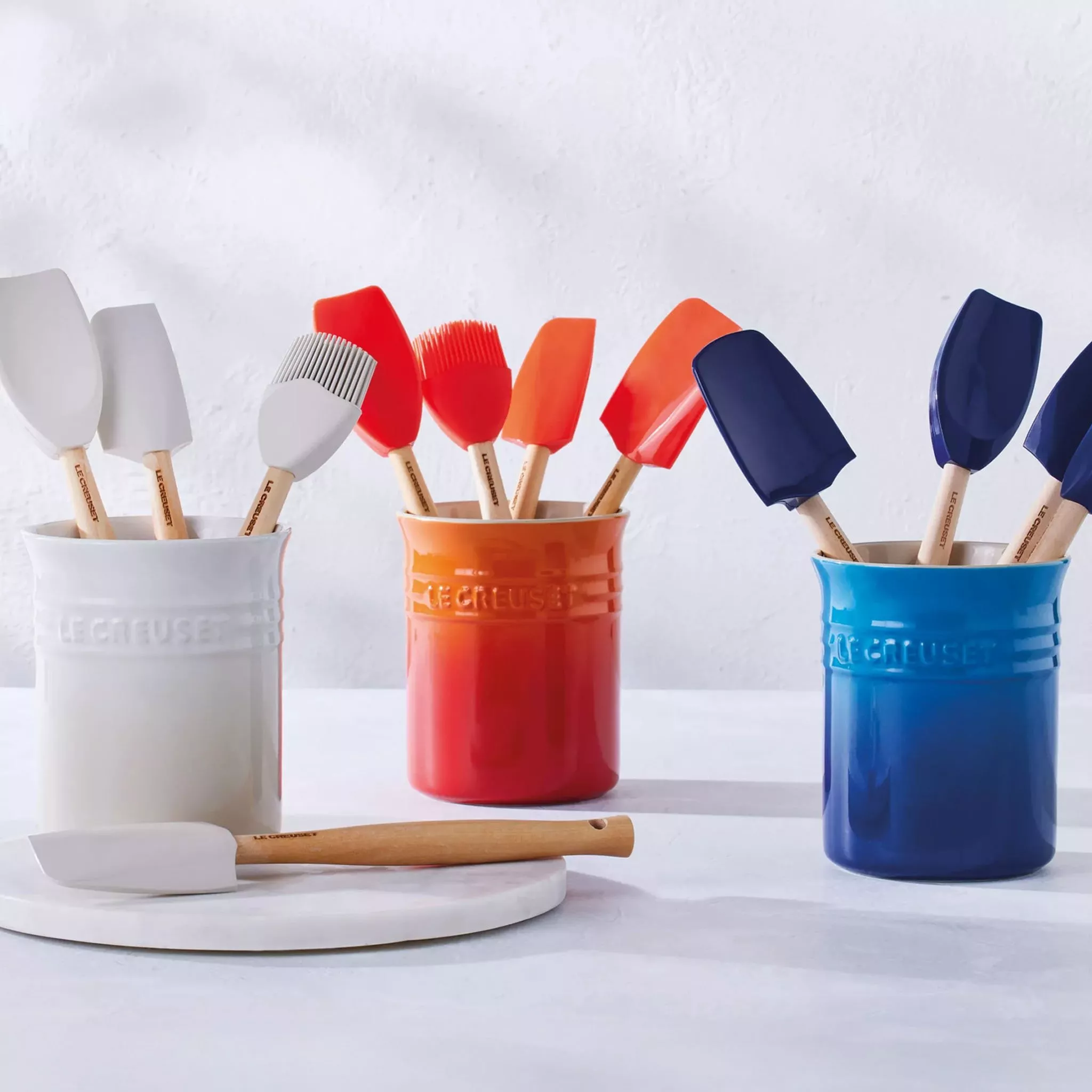 White, red and blue Le Creuset utensil sets in a row
