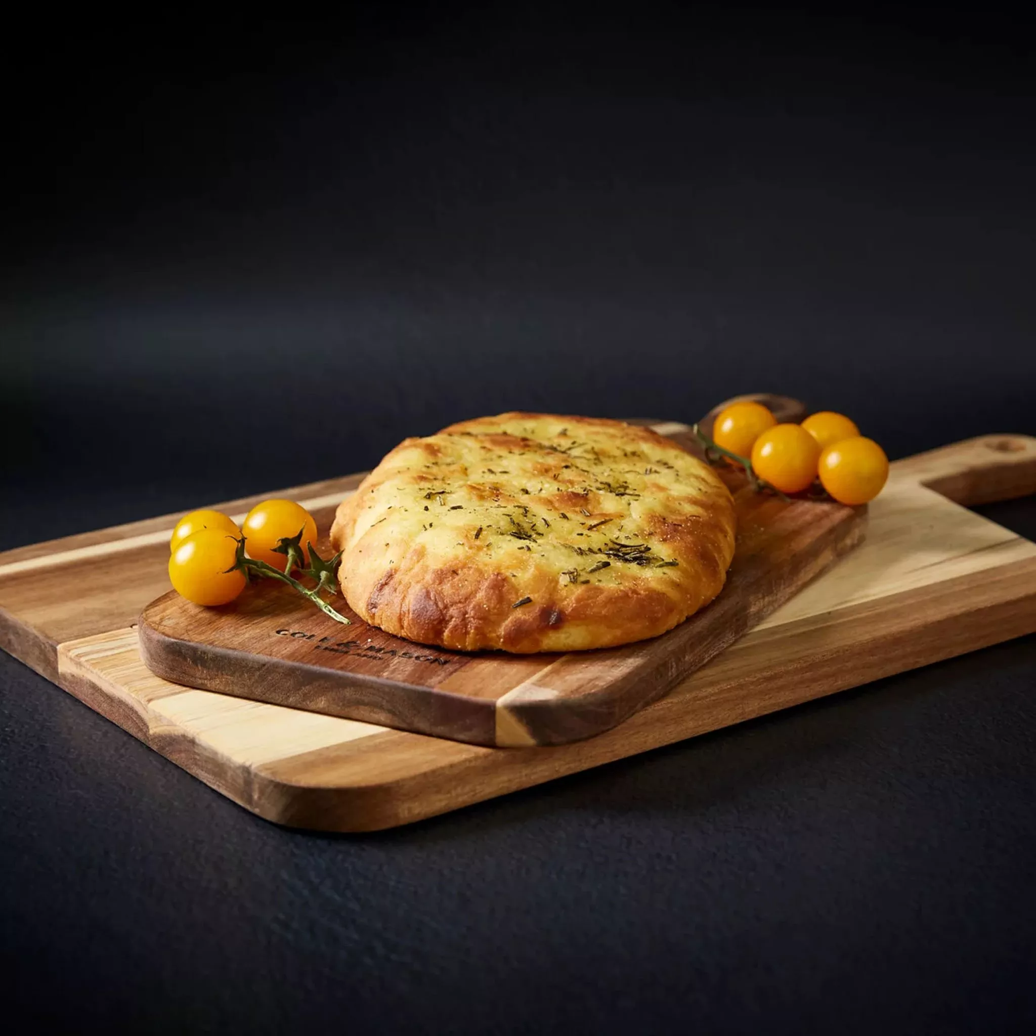 Wooden chopping board with focaccia and tomatoes on it