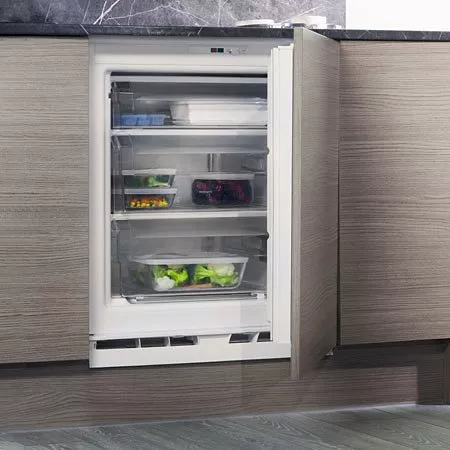 Open integrated under-counter fridge freezer in modern kitchen, showing shelves with fresh food containers