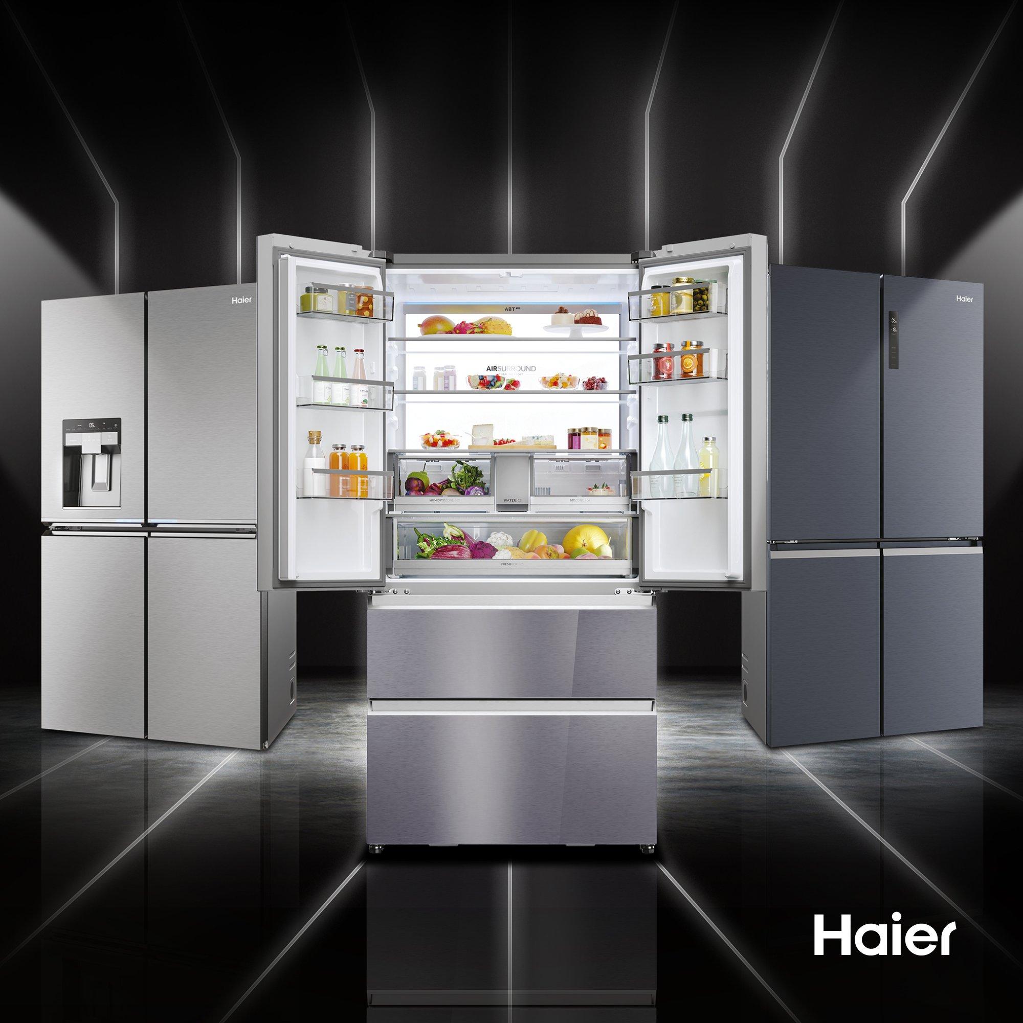 Three Haier fridges side by side. Central Haier fridge has fridge doors open displaying food contents.