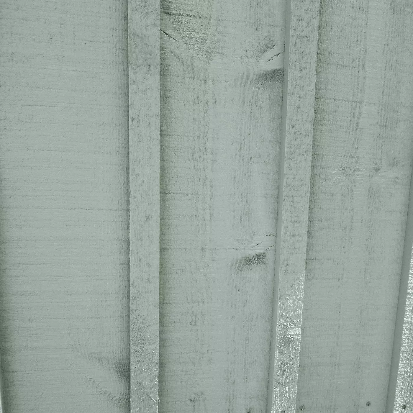 Close-up of weathered grey painted wooden fence panels with vertical slats, outdoor garden texture background