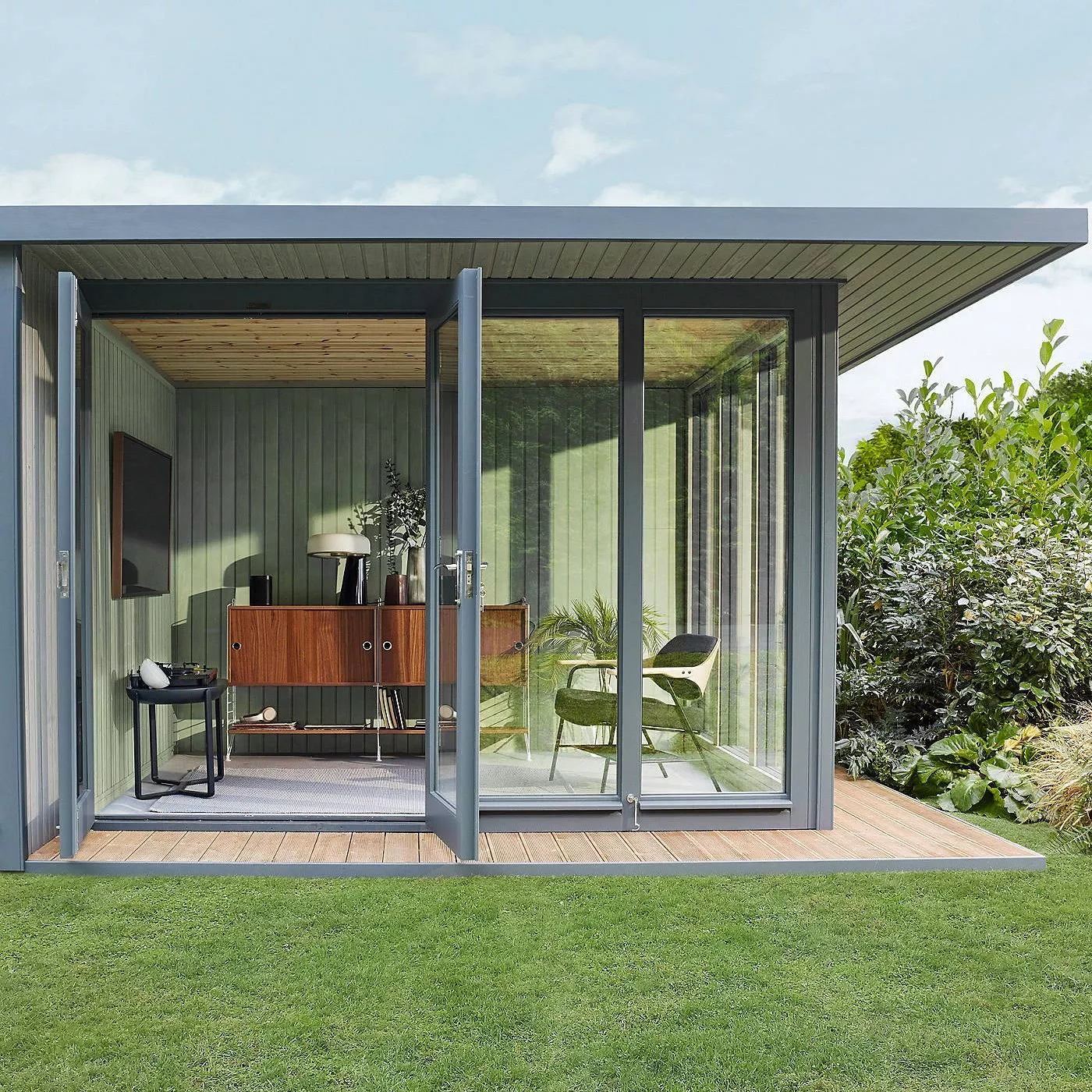 Modern garden office pod with glass doors, timber deck and stylish interior workspace in a green back garden