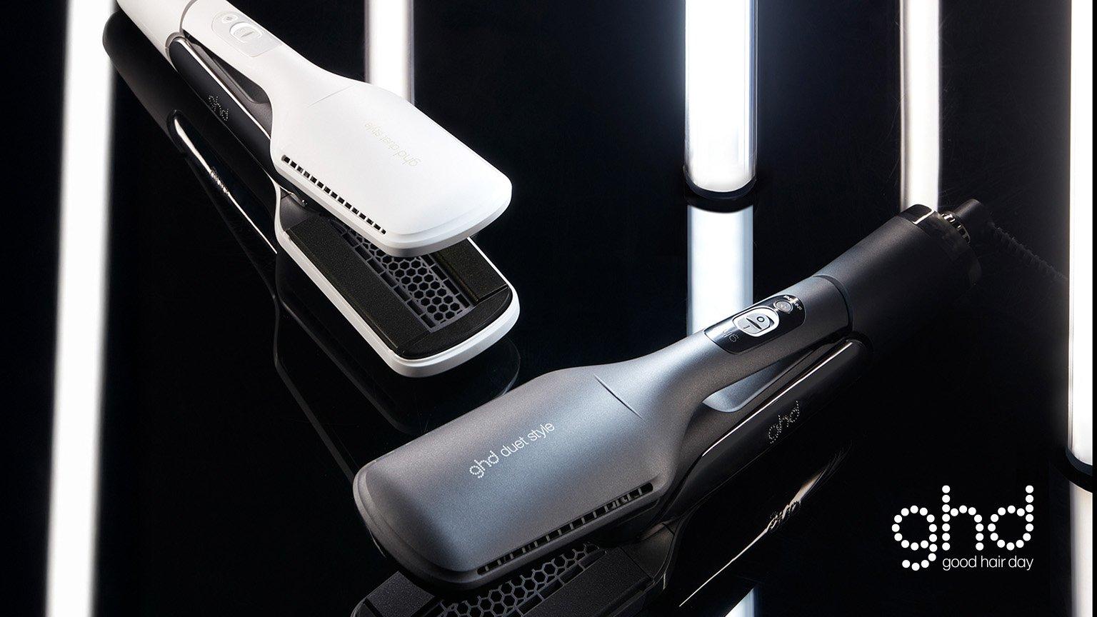 two ghd duet style hot air stylers one in white and one in black on a glossy black reflective surface
