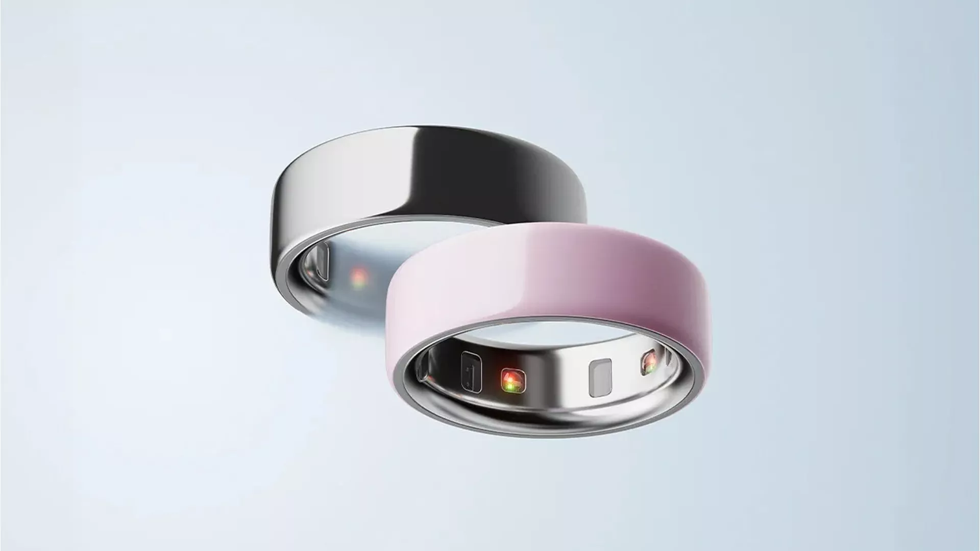 Sleek black and pink smart rings with inner sensors on a light blue background, showcasing wearable technology.