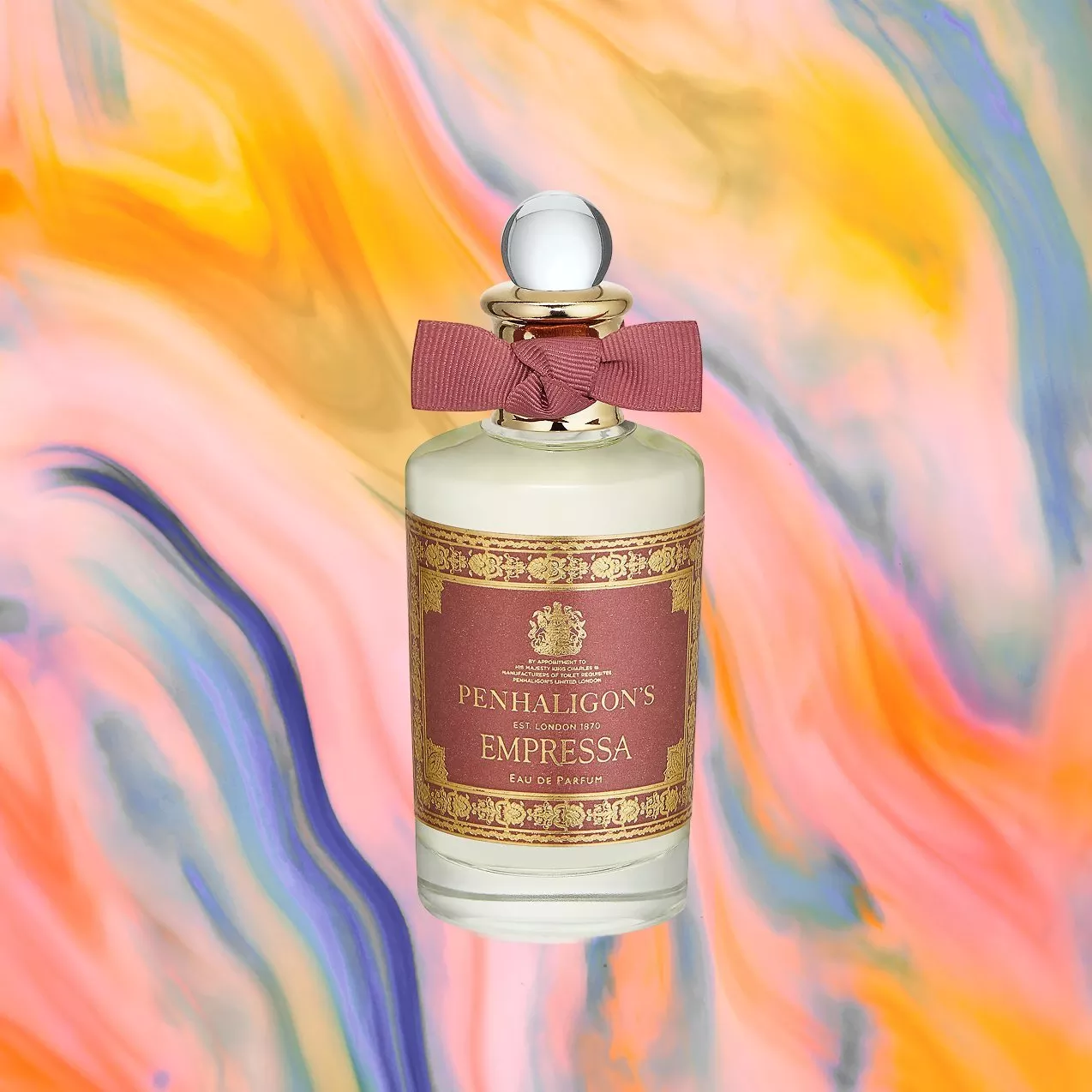 A Penhaligon's Empressa perfume bottle with a red label and bow, set against a colourful, abstract background.