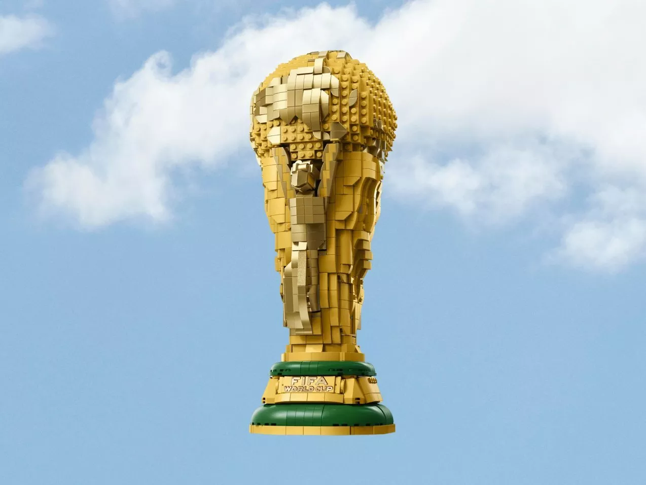 LEGO FIFA World Cup trophy model in gold bricks, centred against a blue sky with soft white clouds