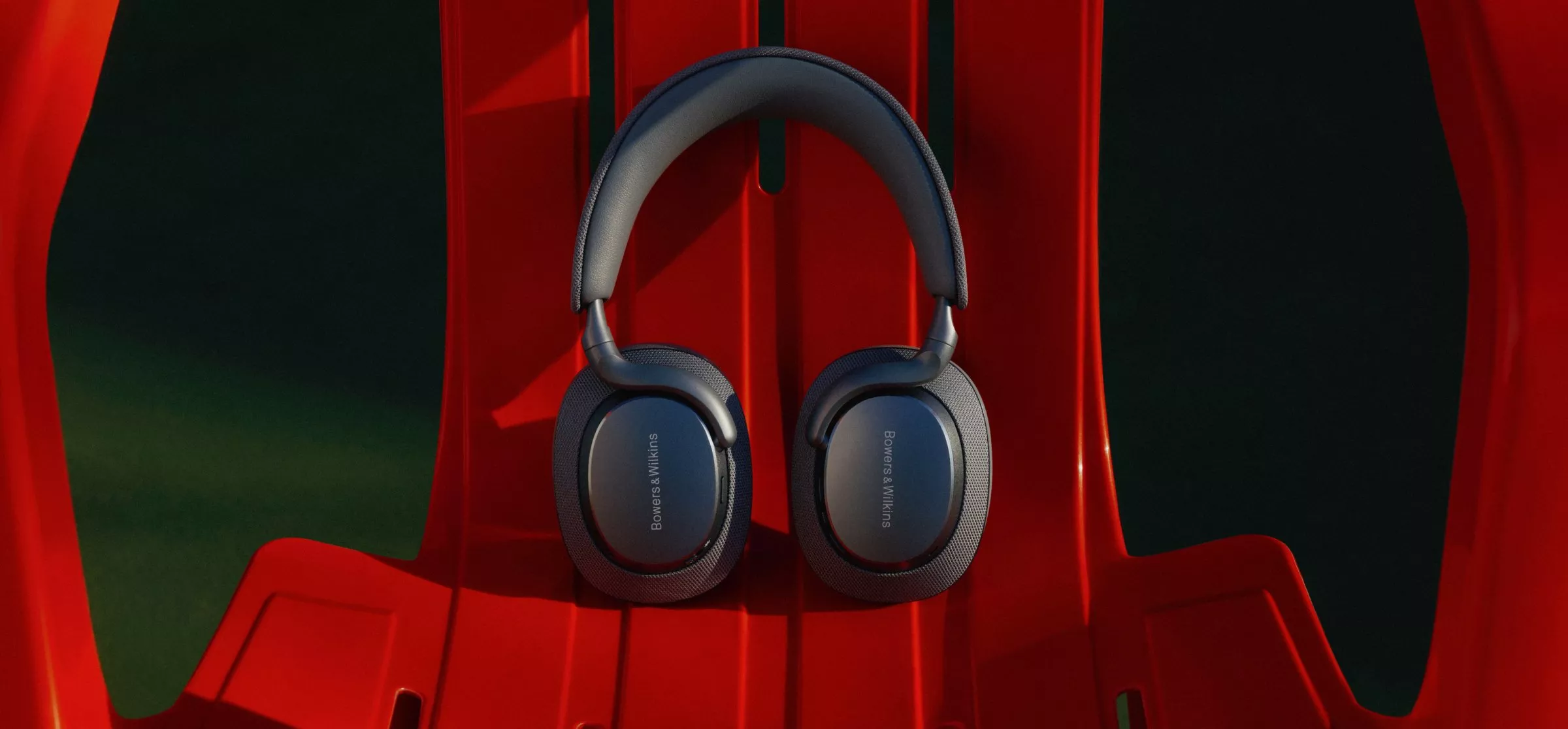 Bowers & Wilkins over-ear wireless headphones on a red outdoor chair, premium audio and noise-cancelling design
