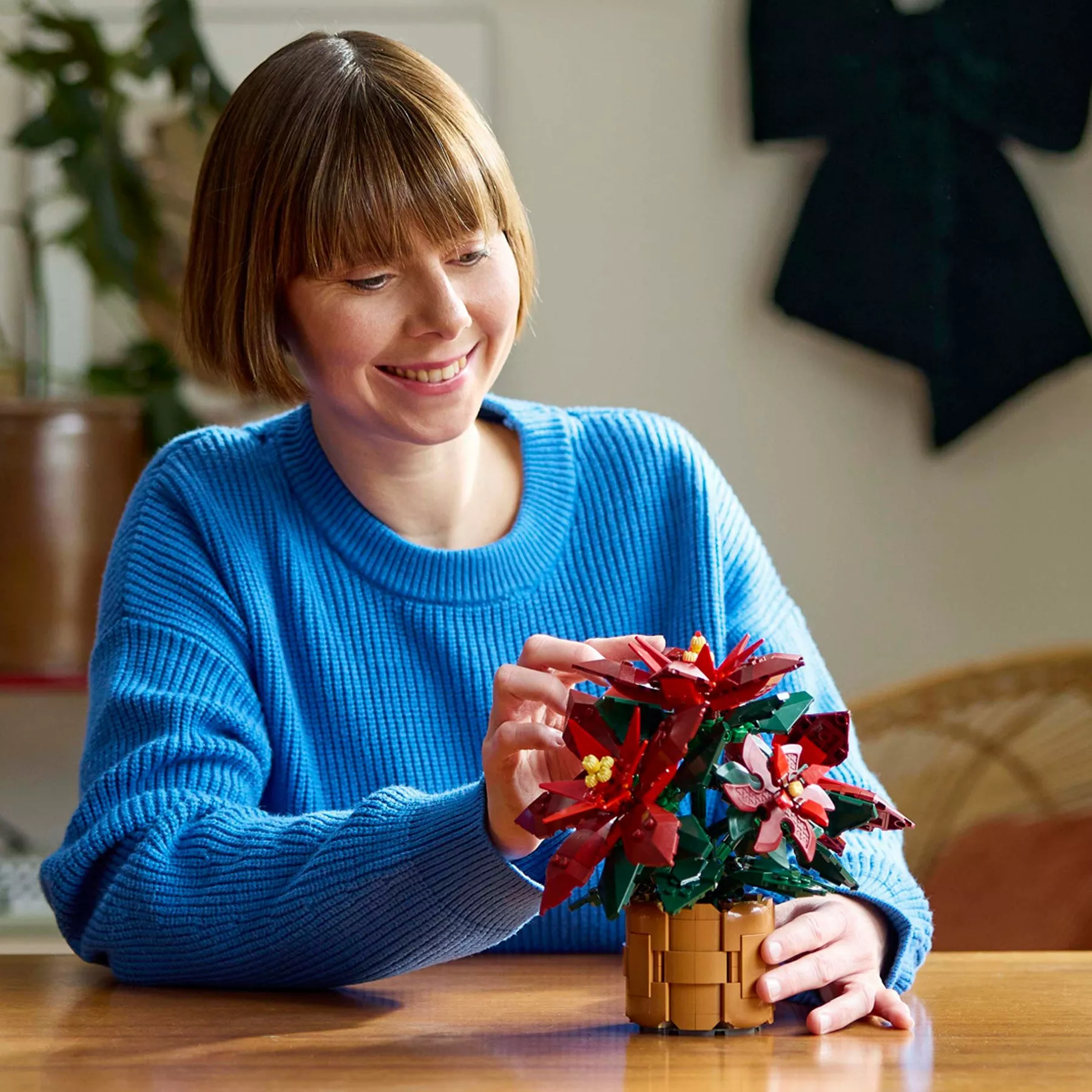 Woman building LEGO Botanicals Poinsettia Plant Set for Adults 10370