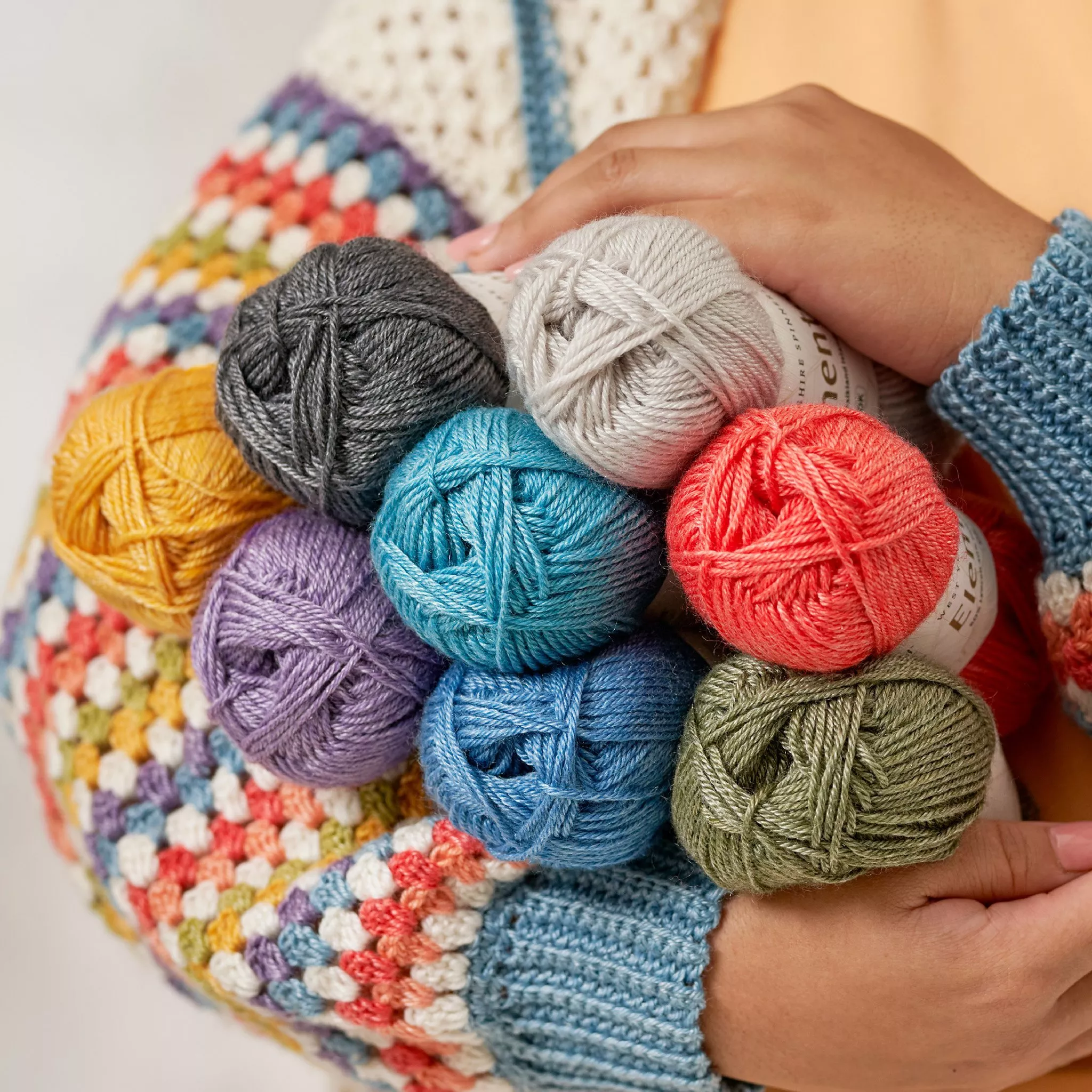 A collection of different coloured yarn in a persons arms