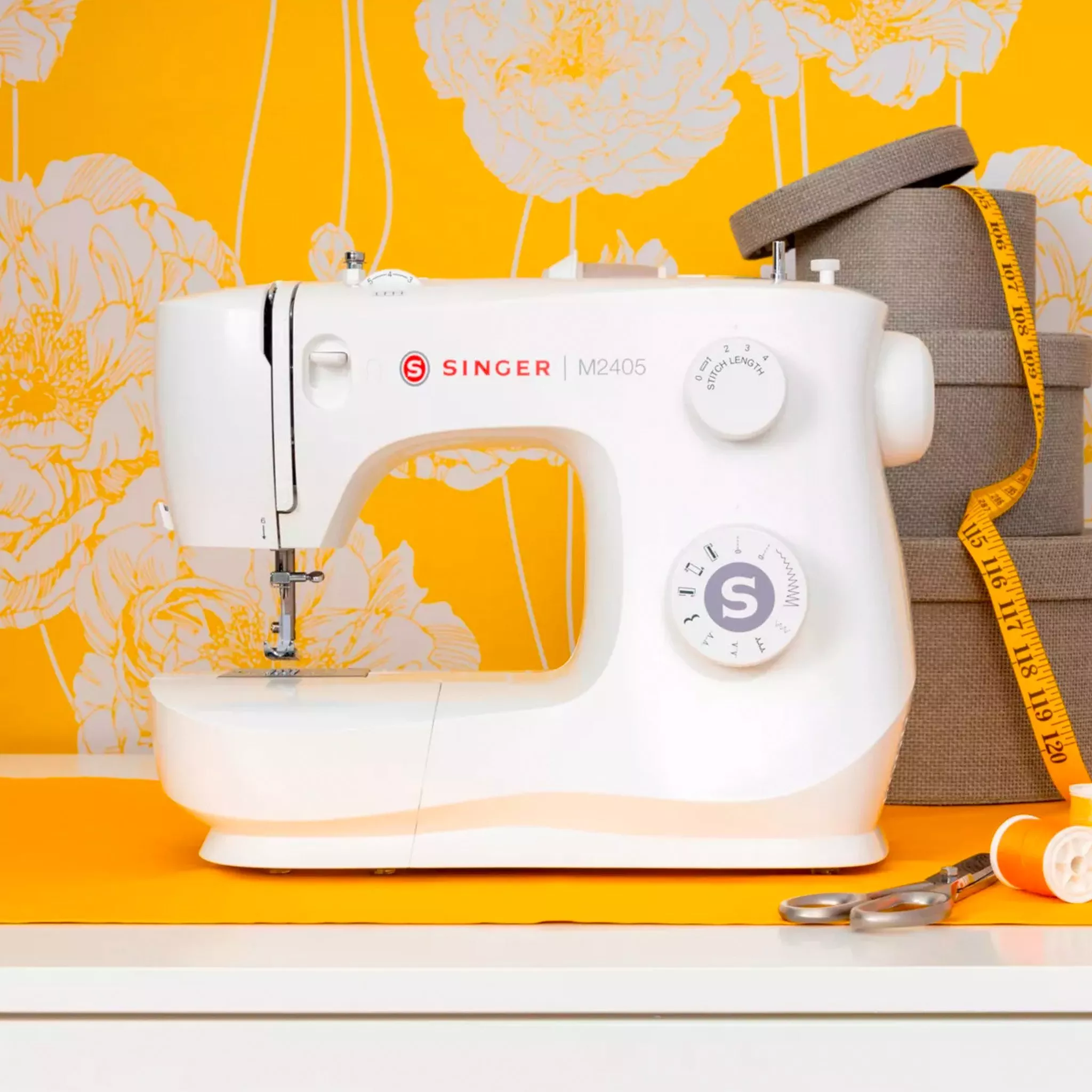 White Singer sewing machine against a yellow wall. Scissors and a tape measure are on the table next to it. 