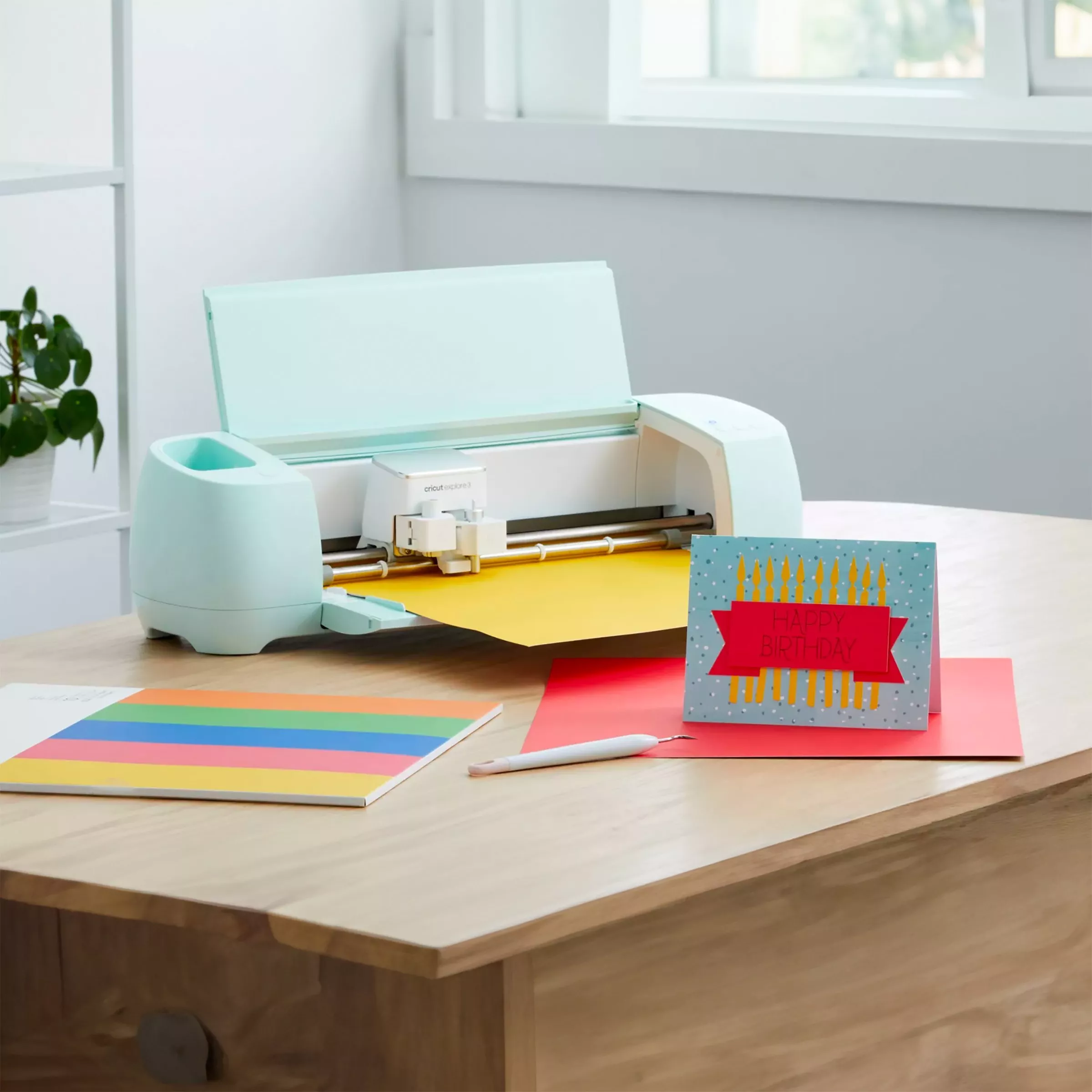 Blue Circut machine with coloured card next to it 
