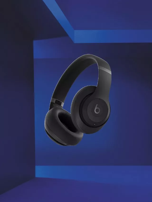 Black Beats wireless over-ear headphones with cushioned earcups, floating in a blue studio background