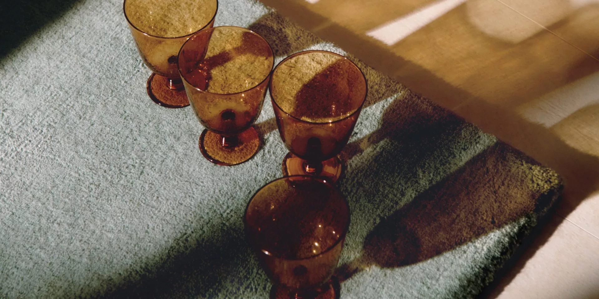 Stylish living room with a patterned blue sofa, vibrant cushions, wooden sideboard, and orange tufted ottoman.