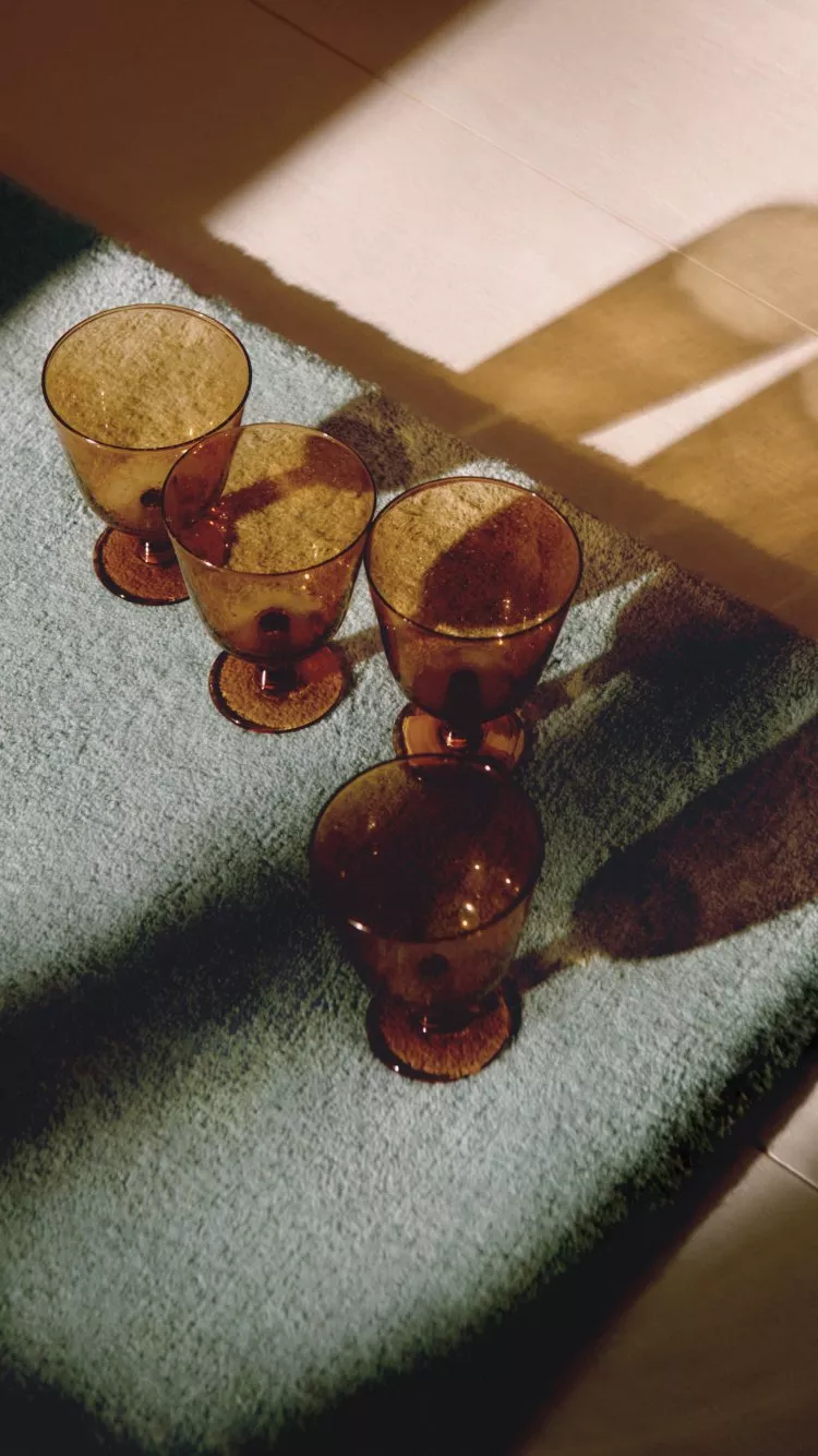 Stylish living room with a patterned blue sofa, orange ottoman, and a wooden sideboard. Decor includes a lamp and artwork.
