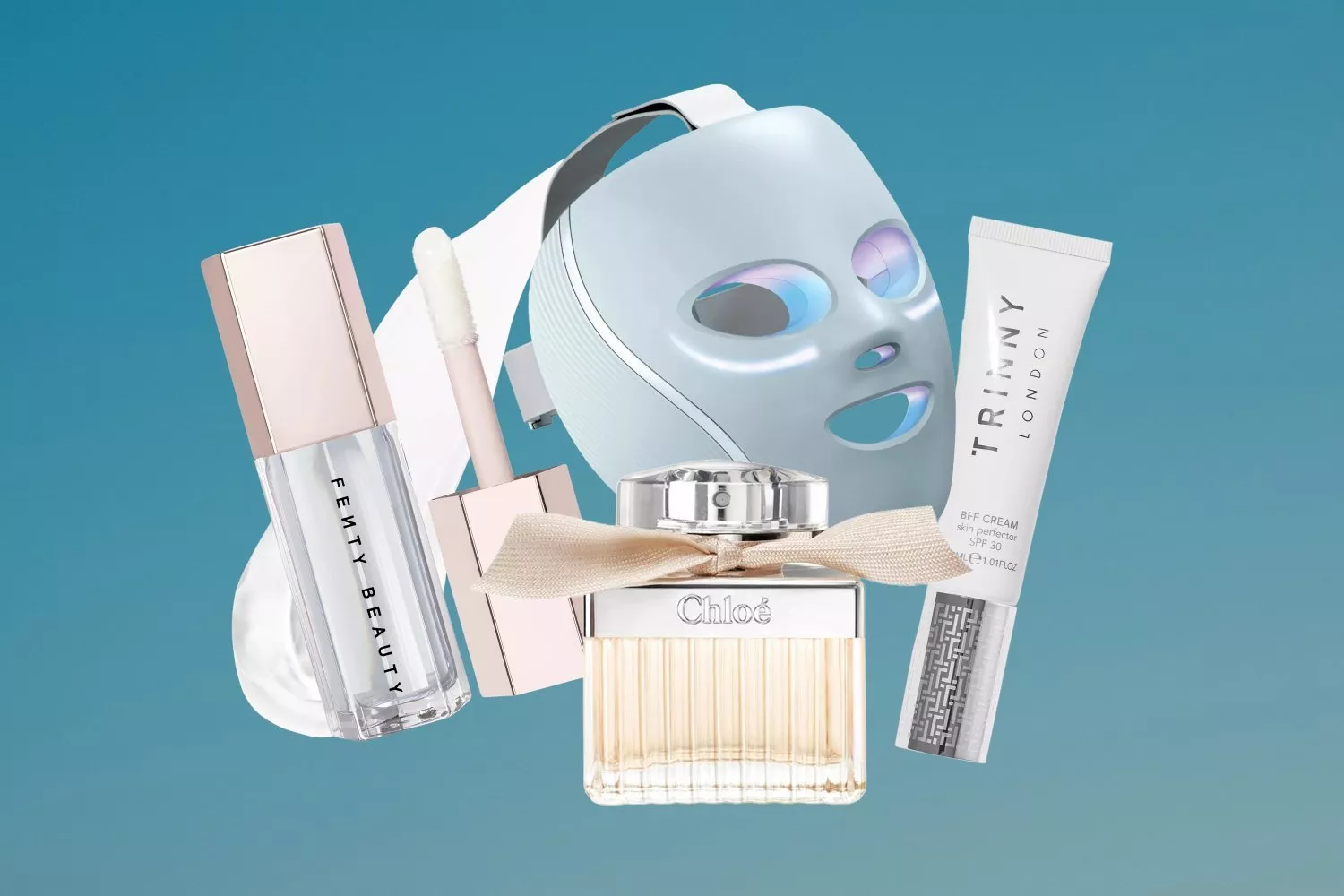 Beauty flat lay with LED face mask, Fenty Beauty gloss, Chloé perfume and Trinny London BFF cream on blue background