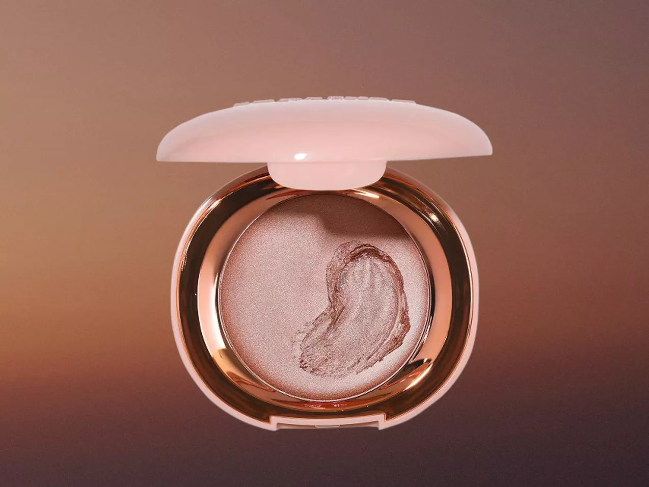 Open rose-gold compact with shimmering highlighter pressed powder, heart-shaped swirl, on soft neutral background