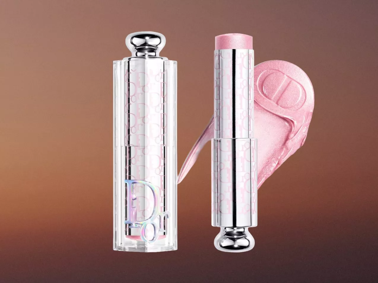 Luxury pink lip gloss in clear silver tube with shimmer swatch on brown background, close-up product shot