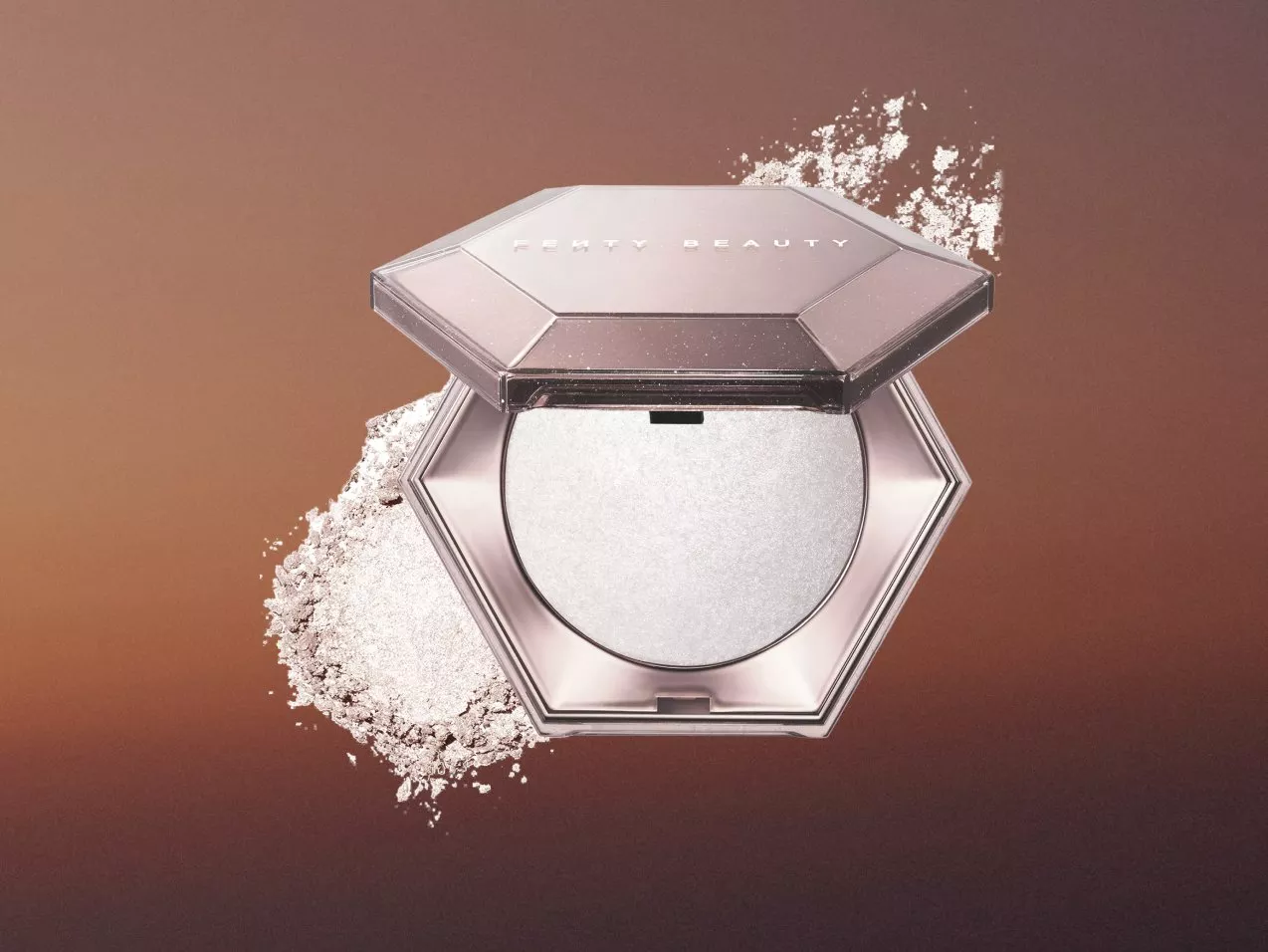 Fenty Beauty highlighter compact with shimmering powder, open case on warm brown background with powder splash