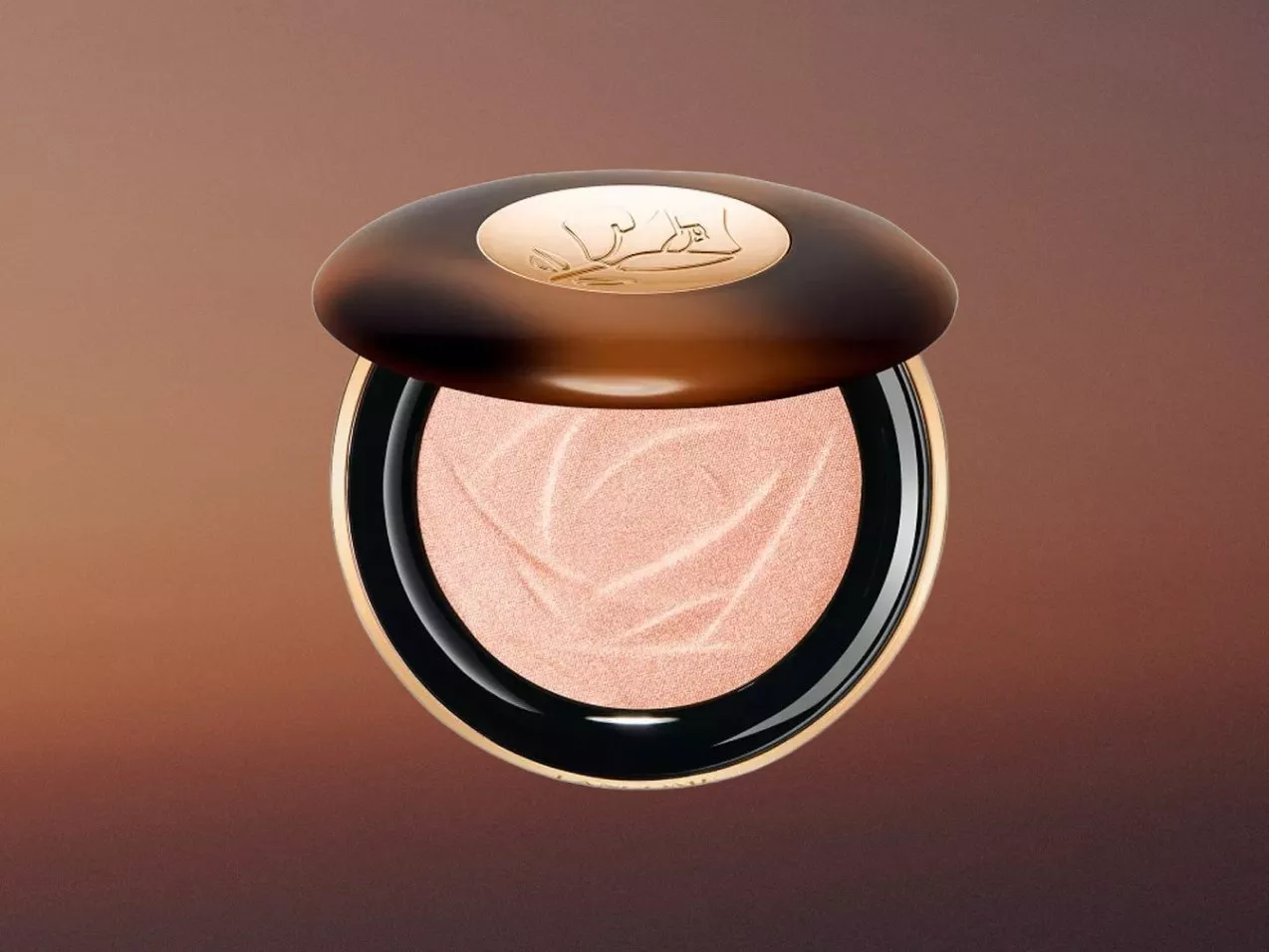 Luxury rose gold highlighter compact with embossed powder and bronze lid, beauty product close-up on brown background