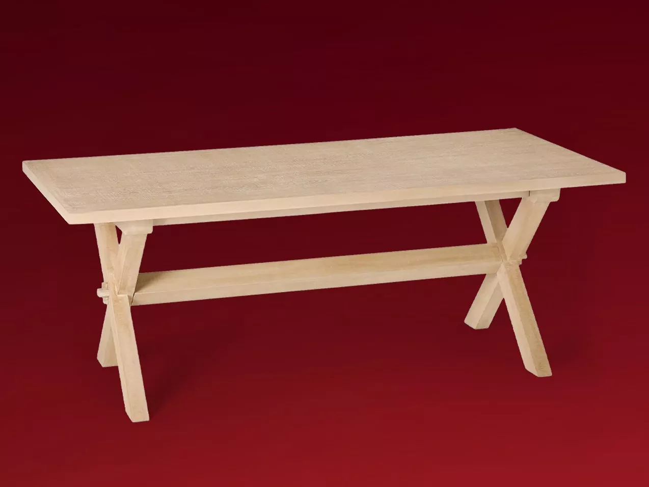 Light oak wooden trestle desk with cross-braced legs and lower stretcher, on deep red background