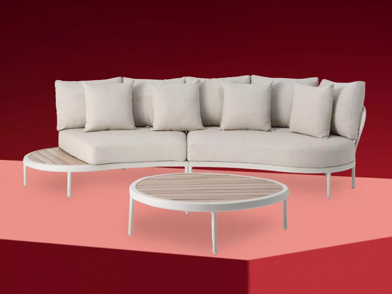 Modern outdoor lounge sofa with beige cushions and matching round coffee table on red backdrop