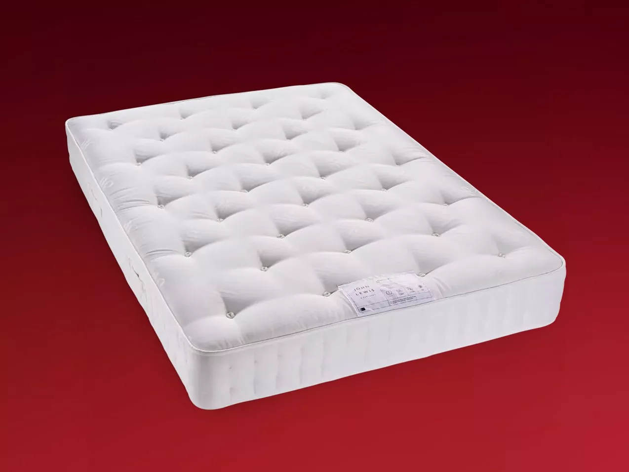 White tufted pocket sprung mattress with stitched edge, shown on red background