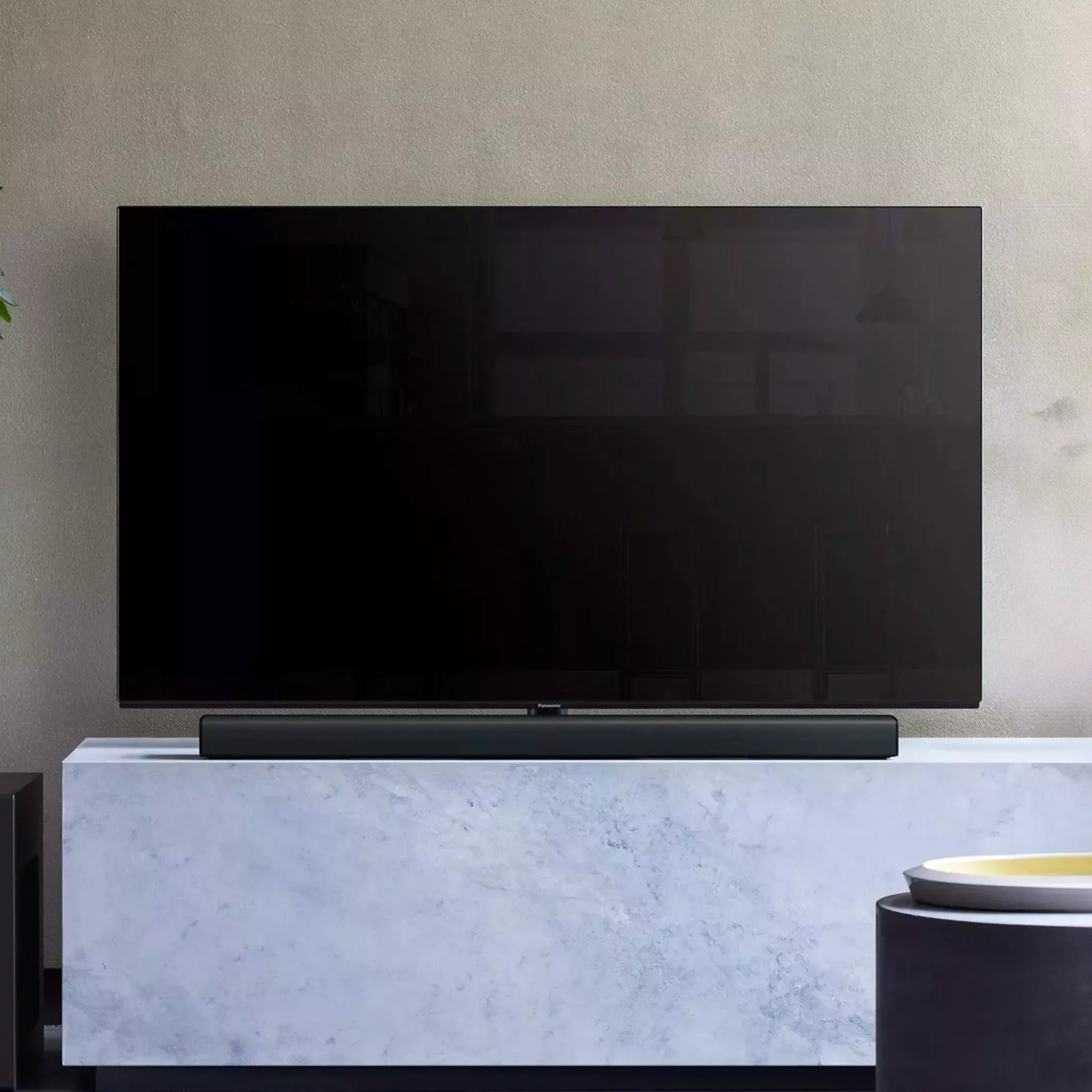 Black soundbar infront of TV on a TV stand 