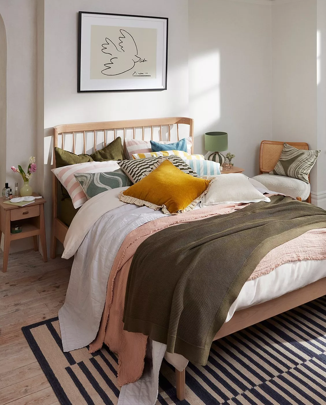 wooden bed decorated with scatter cushions and colourful throws