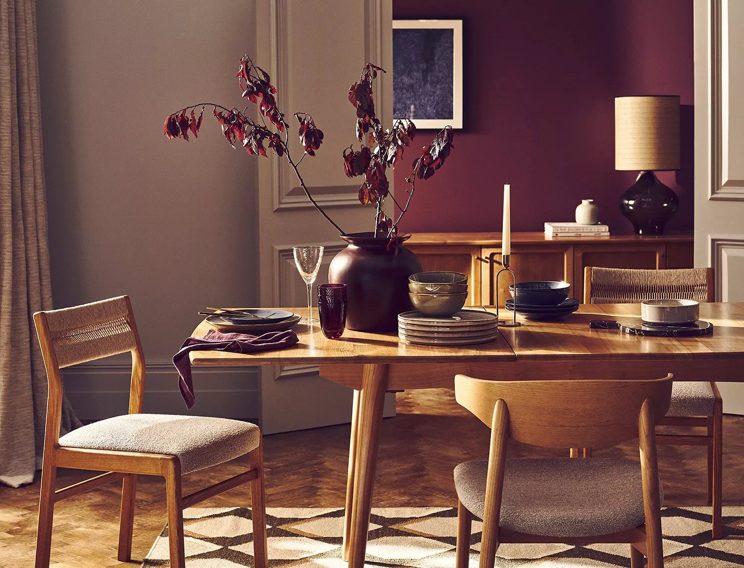 wooden dining table and chairs with burgundy settings and plant