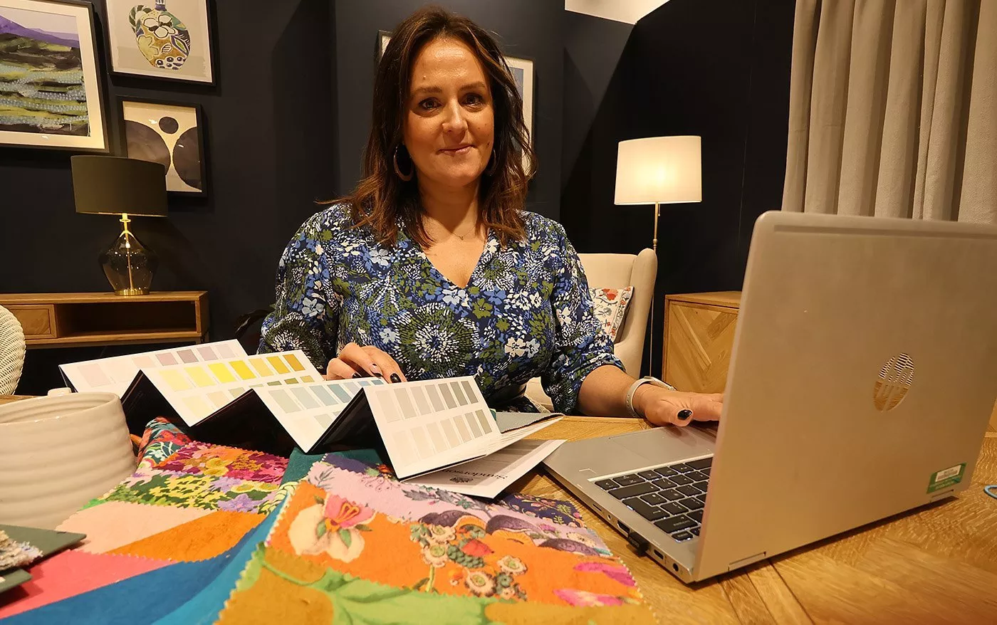 Person sitting at a desk with paint swatches and a laptop