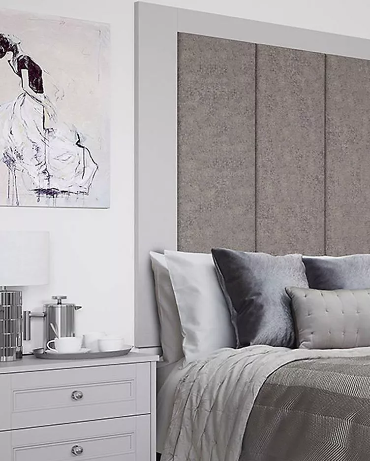 Modern bedroom with grey headboard, abstract art, and a stylish bedside table with a lamp and coffee set.