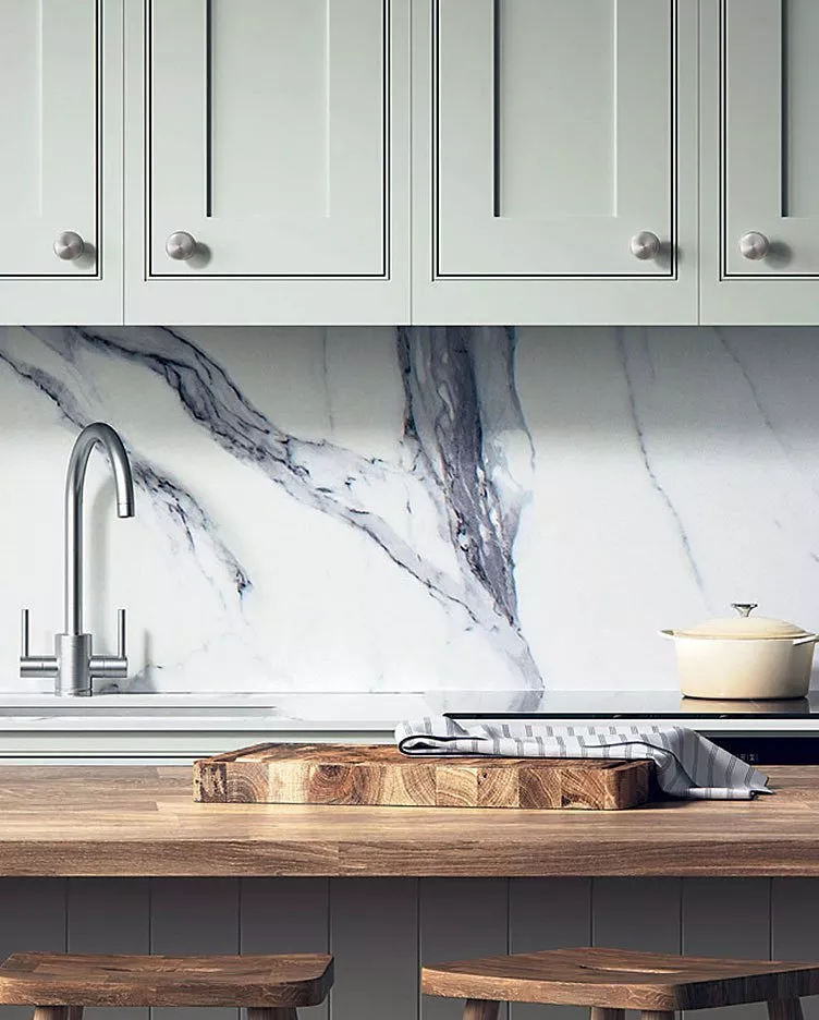 Modern kitchen with light cabinets, marble backsplash, wooden counter, and stainless steel tap, creating a sleek look.