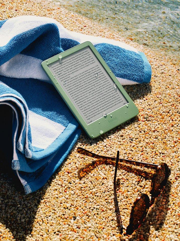 Amazon Kindle, sunglasses and beach towel on a sandy beach