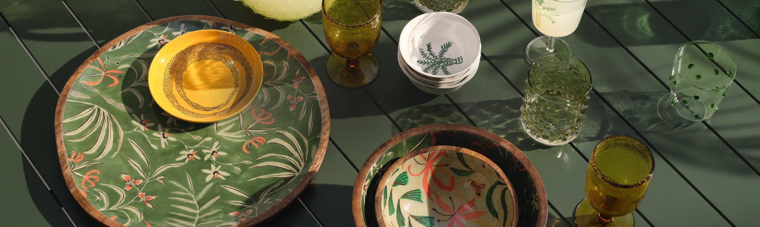 Outdoor summer dining plates, glasses and bowls on a green garden table