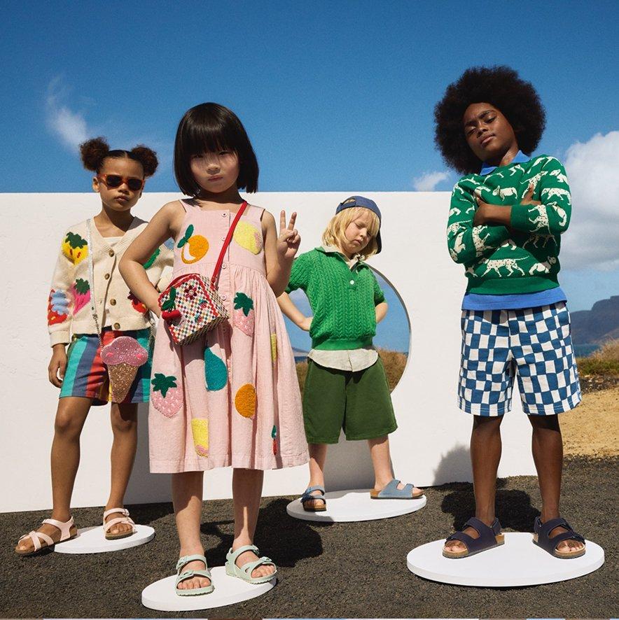 Four kid models standing and wearing various bold and colourful holiday outfits