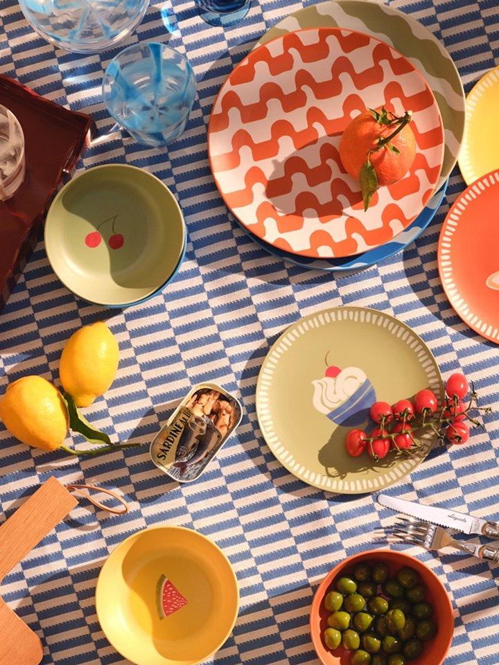 A selection of picnicware products displayed on a blue-striped picnic blanket