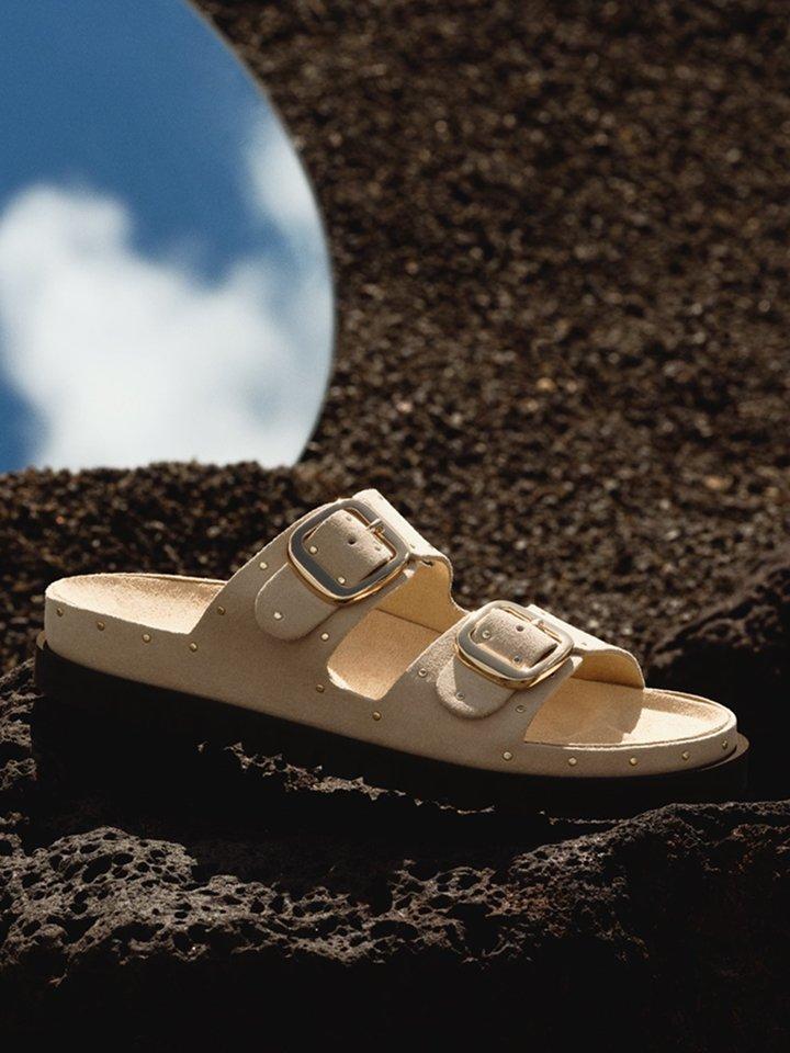 A women’s sandal displayed on black rock.