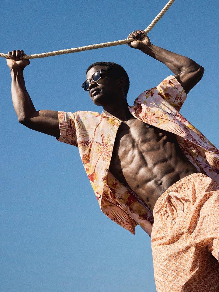 A male model posing in a shirt and shorts