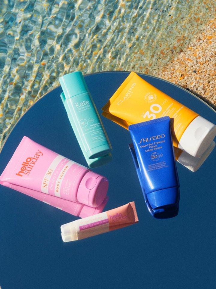 A variety of SPF sun creams laid out on a table at the beach