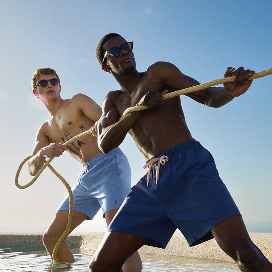 Two male models standing with their feet in water, playing tug of war.