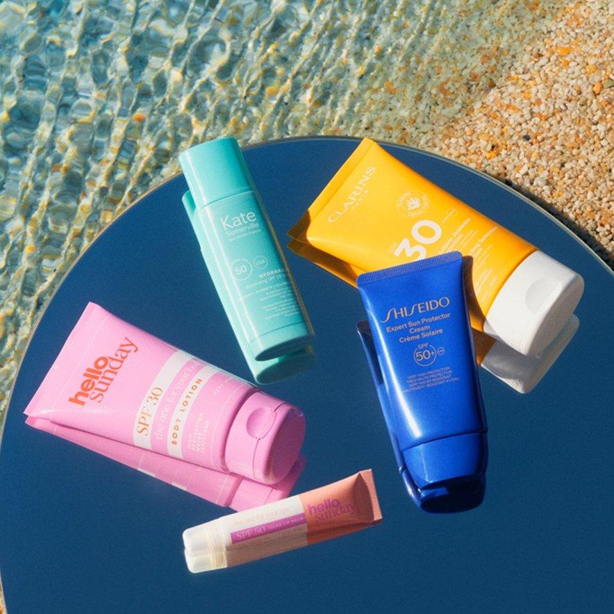 A variety of SPF sun creams laid out on a table at the beach