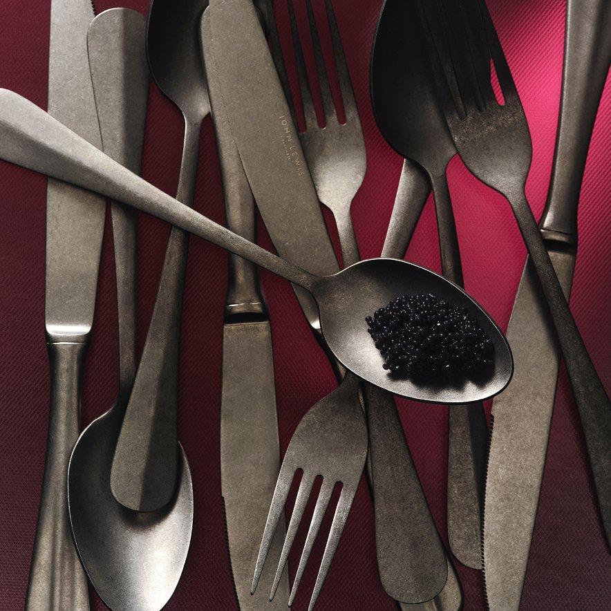 Close-up of silver cutlery on display with a red background