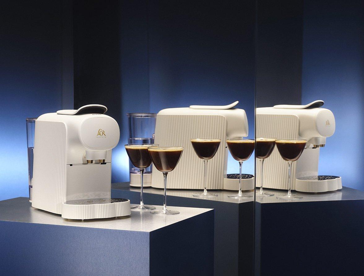 L'OR Barista coffee machine on a blue plinth against a mirror backdrop