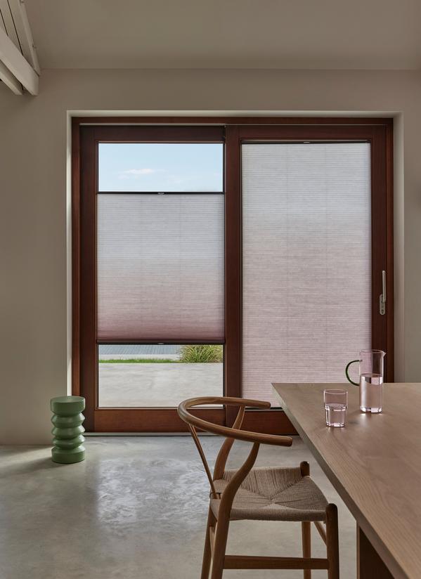 Modern dining room with wooden sliding doors and pleated blinds, letting in soft daylight and garden view