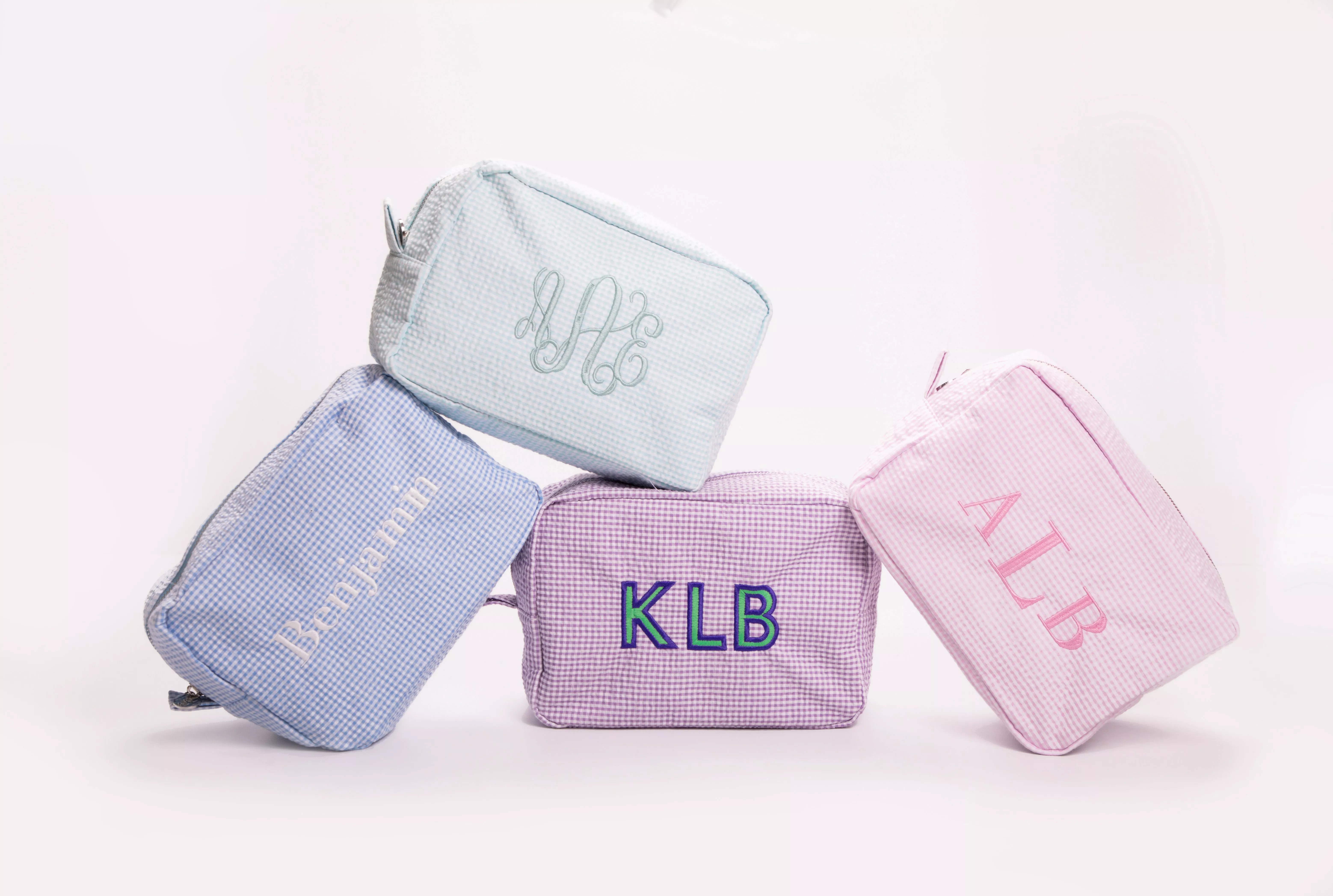 Personalised gingham wash bags in pastel blue, lilac and pink with embroidered monograms on a white background